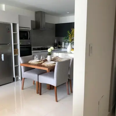 a kitchen with a wooden table and chairs and a kitchen with a refrigerator at Piantini’s Skylight in Santo Domingo