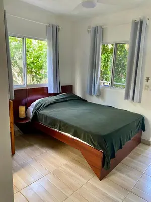 a bedroom with a large bed with two windows at Kite House Cabarete across Kite Beach in Cabarete