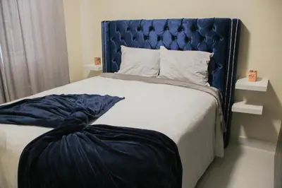 a bedroom with a bed with a blue headboard at Las Cayenas Residéncial in Santo Domingo