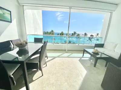 a living room with a table and a view of the ocean at 703 Marbella 2 bedrooms Beachfront Beautiful Apartment in San Pedro de Macorís