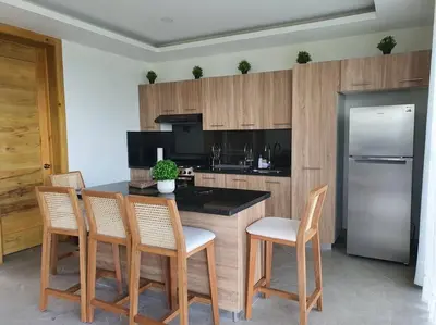 a kitchen with a island with chairs and a refrigerator at Villa en la montaña in Jarabacoa