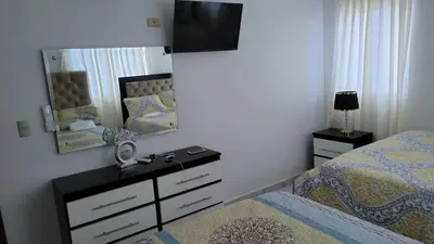 a bedroom with a bed and a dresser and a mirror at Madome Aparta Hotel in Pedernales
