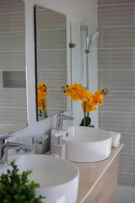 a bathroom with two sinks and a mirror and yellow flowers at Beachfront penthouse - Amar'e Aparthotel & Spa in Las Terrenas