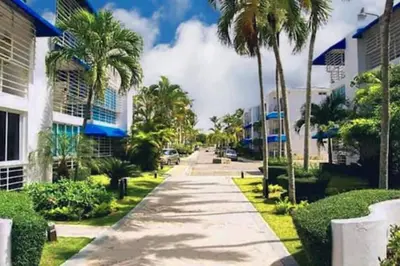 a street in front of some buildings with palm trees at Acceso Exclusivo A Club De Playa Totalmente Gratis, Areas Sociales Con BBQ, Piscina, Jacuzzi, Gazebos, Baños, Ducha Exterior, Wifi, Netflix Y Al Lado De Minimarkets, Restaurantes, Bares, Tiendas, Campos De Golf, Hoteles, Bancos Comerciales, Etc in Guayacanes