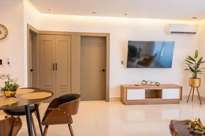 a living room with a table and a tv on the wall at Top Floor in Luxury Tower in Santiago de los Caballeros