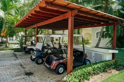 two golf carts parked under a pavilion in front of a house at Special Offer, Iberostar Apartment Milagro 3BDR Pool, Beach in Punta Cana