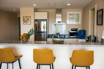 a kitchen with a counter with three bar chairs at Special Offer, Iberostar Apartment Milagro 3BDR Pool, Beach in Punta Cana