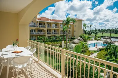 a balcony with a table and chairs and a resort at Spacious Iberosta ApartmentSueno - 3BDR Pool, Beach, WiFi in Punta Cana