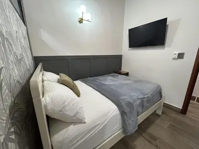 a bedroom with a bed with a tv on the wall at Beach Apartment Villas Jubey, Emotion access in Juan Dolio