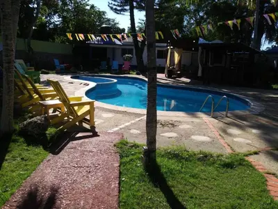 a swimming pool with two chairs and a tree at Hacienda de Flores in Guayacanes