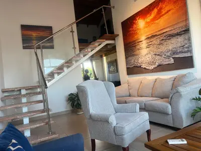 a living room with a couch and a staircase at Armonia De Las Terrenas Gorgeous Penthouse in Las Terrenas