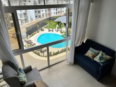 a living room with a view of a pool through a window at Armonia De Las Terrenas Gorgeous Penthouse in Las Terrenas