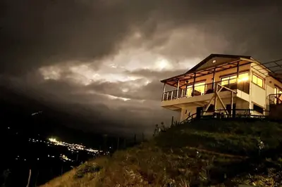 a house on top of a hill at night at La Casita de Charo 1, disfruta de tiempo memorable en la montaña in Constanza