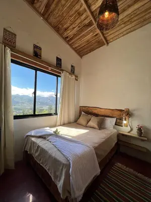 a bedroom with a bed and a large window at La Casita de Charo 1, disfruta de tiempo memorable en la montaña in Constanza