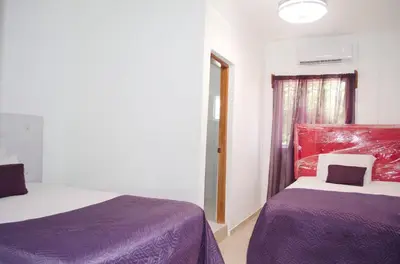 a room with two beds with purple sheets and a window at Hotel las Nina in Paraíso