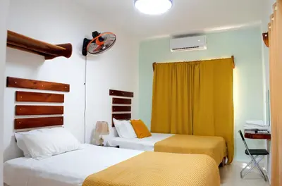 a bedroom with two beds and a desk at Hotel las Nina in Paraíso