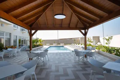 a patio with tables and chairs and a swimming pool at Super 8 by Wyndham Manzanillo in Pepillo Salcedo