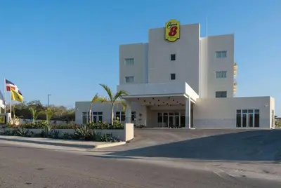 a large white building with a sign on it at Super 8 by Wyndham Manzanillo in Pepillo Salcedo