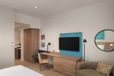 a bedroom with a desk with a tv and a couch at Hilton Garden Inn La Romana in La Romana