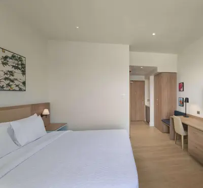 a bedroom with a large white bed and a desk at Hilton Garden Inn La Romana in La Romana