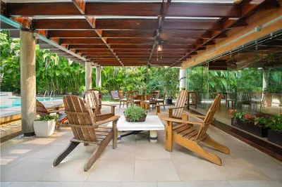 a patio with wooden chairs and tables and a pool at Fontana di Rosa, African Style Villa Casa de Campo in La Romana
