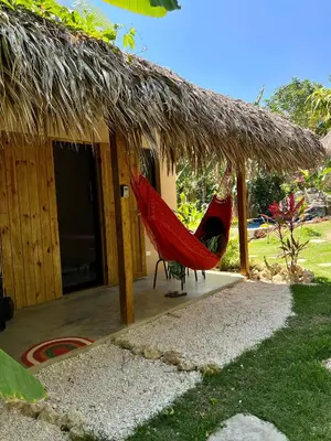 a house with a hammock and a thatch roof at Casita Chinola - Playa El Encuentro in Bombita