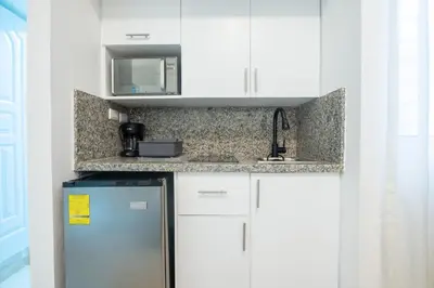 a kitchen with white cabinets and a refrigerator at Estudio 9 en la Zona Colonial in Santo Domingo