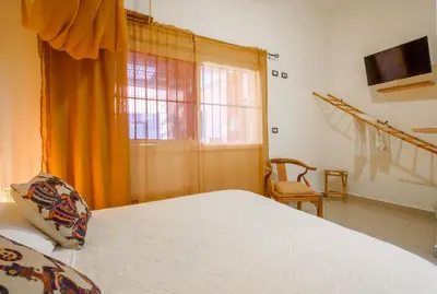 a bedroom with a large bed and a window at Hostal Mamà Mambò - Zona Colonial in Santo Domingo