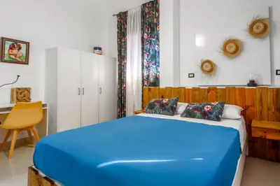 a bedroom with a blue bed and a desk at Hostal Mamà Mambò - Zona Colonial in Santo Domingo