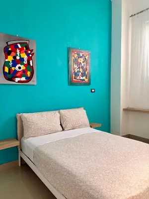a bedroom with a bed with a blue wall at Hostal Mamà Mambò - Zona Colonial in Santo Domingo