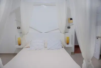 a white bed with white curtains in a room at Hostal Mamà Mambò - Zona Colonial in Santo Domingo