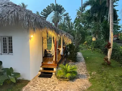 a small house with a thatched roof and a porch at Playa Bonita 4 minute walk from our private Villa Anantara Bonita in Las Terrenas