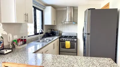 a kitchen with a stove and a refrigerator at Bello apartamento en Evaristo Morales, 1 BR in Santo Domingo