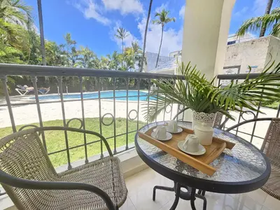 a table and chairs on a balcony with a view of a pool at Private Pool View 2BDR in Los Corales Punta Cana in Punta Cana