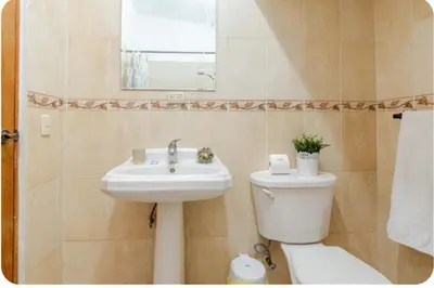 a bathroom with a sink and a toilet and a mirror at Amplio apartmento in Santo Domingo