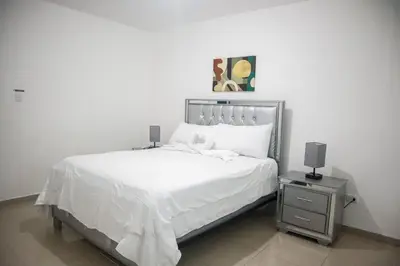 a bedroom with a white bed and a night stand at Salt Air & City Vibe Awaits! Just Minutes to Beach in San Felipe de Puerto Plata