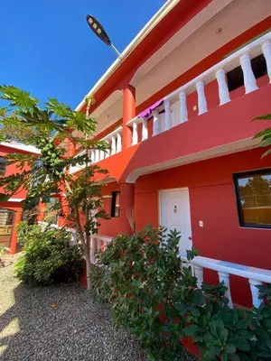 a red building with a tree in front of it at Villa KIKI Ensenada in Punta Rucia