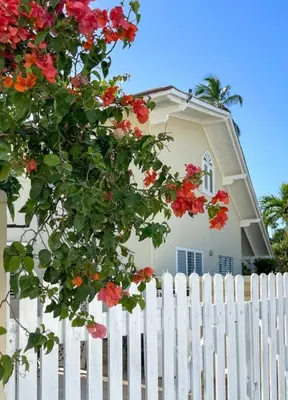 a white fence in front of a white house with flowers at Casa Alegria Beach Cottage in Las Terrenas