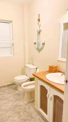 a white bathroom with a toilet and a sink at Casa Alegria Beach Cottage in Las Terrenas