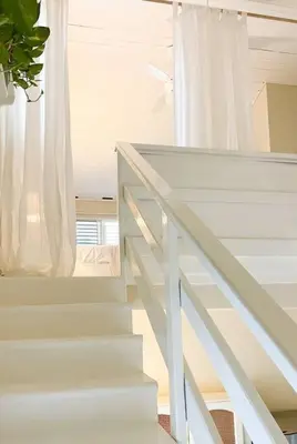 a white staircase with a window and white curtains at Casa Alegria Beach Cottage in Las Terrenas