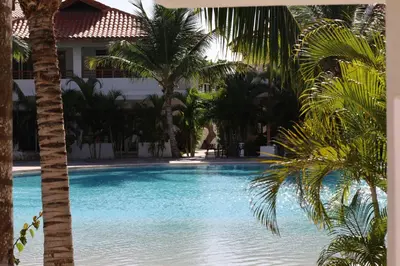a swimming pool with palm trees and a building at Paraiso Bayahibe by Mireya in Bayahibe