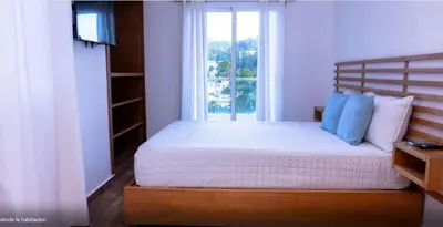 a bedroom with a bed with a large window at Samaná Suites Hotel by Habita in Santa Bárbara de Samaná