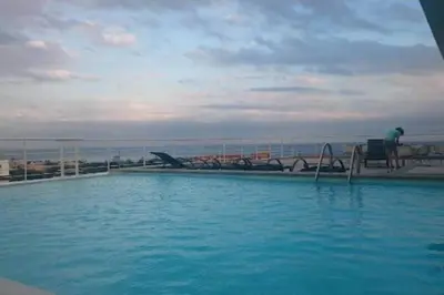a man sitting on a bench next to a swimming pool at Lincoln Suite Pool - Gym - Sauna in Santo Domingo