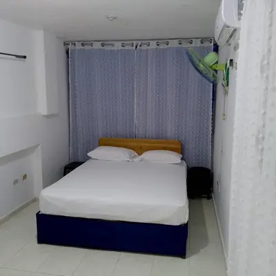 a bed in a small room with a blue curtain at Hotel Ningo in Santa Bárbara de Samaná