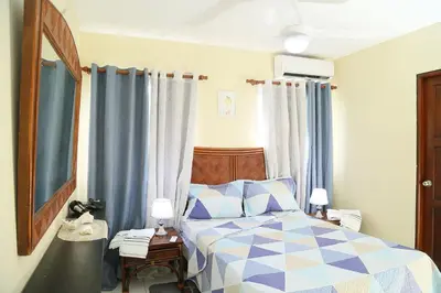 a bedroom with a bed with a blue and white comforter at Apto CALETA BEACH 3HAB in La Romana
