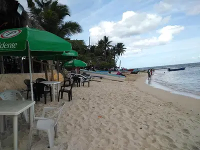 a beach with chairs and umbrellas and the ocean at Apto CALETA BEACH 3HAB in La Romana