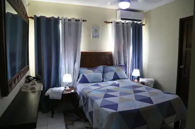 a bedroom with a blue and white bed with blue curtains at Apto CALETA BEACH 3HAB in La Romana