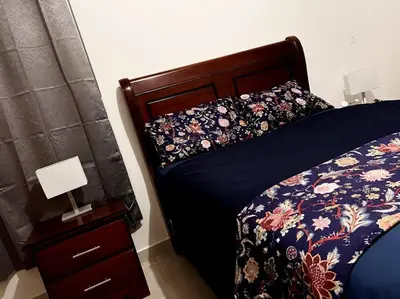 a bedroom with a bed with a blue comforter and a night stand at Outstanding Pent House w/Jacuzzi in Santiago de los Caballeros