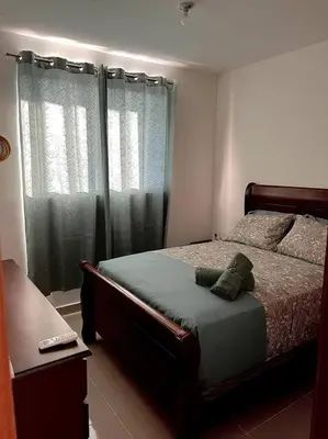 a bedroom with a bed and a window with curtains at Magnificent Pent House w/Jacuzzi in Santiago de los Caballeros