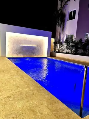 a blue swimming pool in front of a house at Magnificent Pent House w/Jacuzzi in Santiago de los Caballeros
